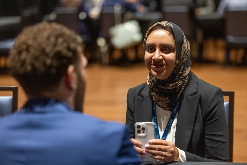 Two attendees talking across a table, one smiling